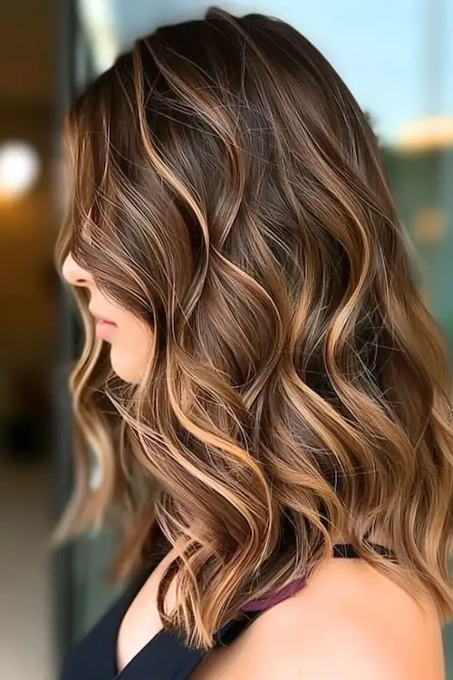 Dark brown hair with caramel and strawberry highlights creating a warm, vibrant effect