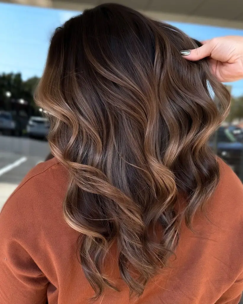 Soft curls with honey-caramel highlights on brunette hair