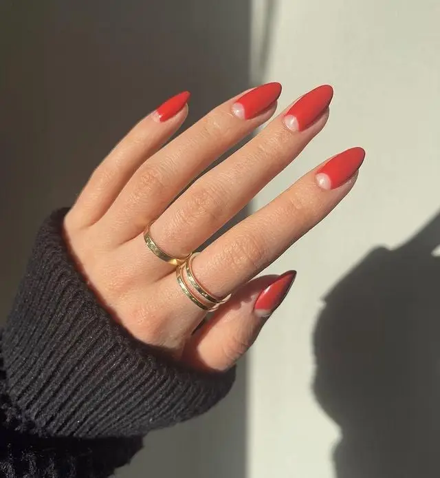 Glossy red nails with gold glitter accents and rhinestone details