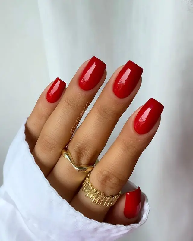 Ruby red nails with glossy finish and subtle jewel accents