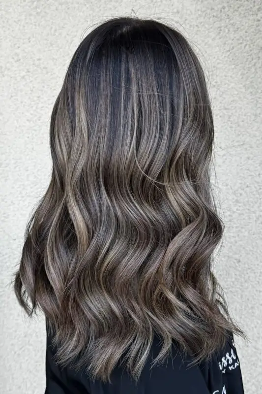 Black hair with ashy balayage fading into soft silver-grey highlights