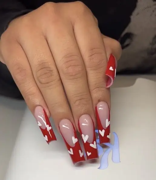 Bright pink Valentine’s nails with bold red heart patterns