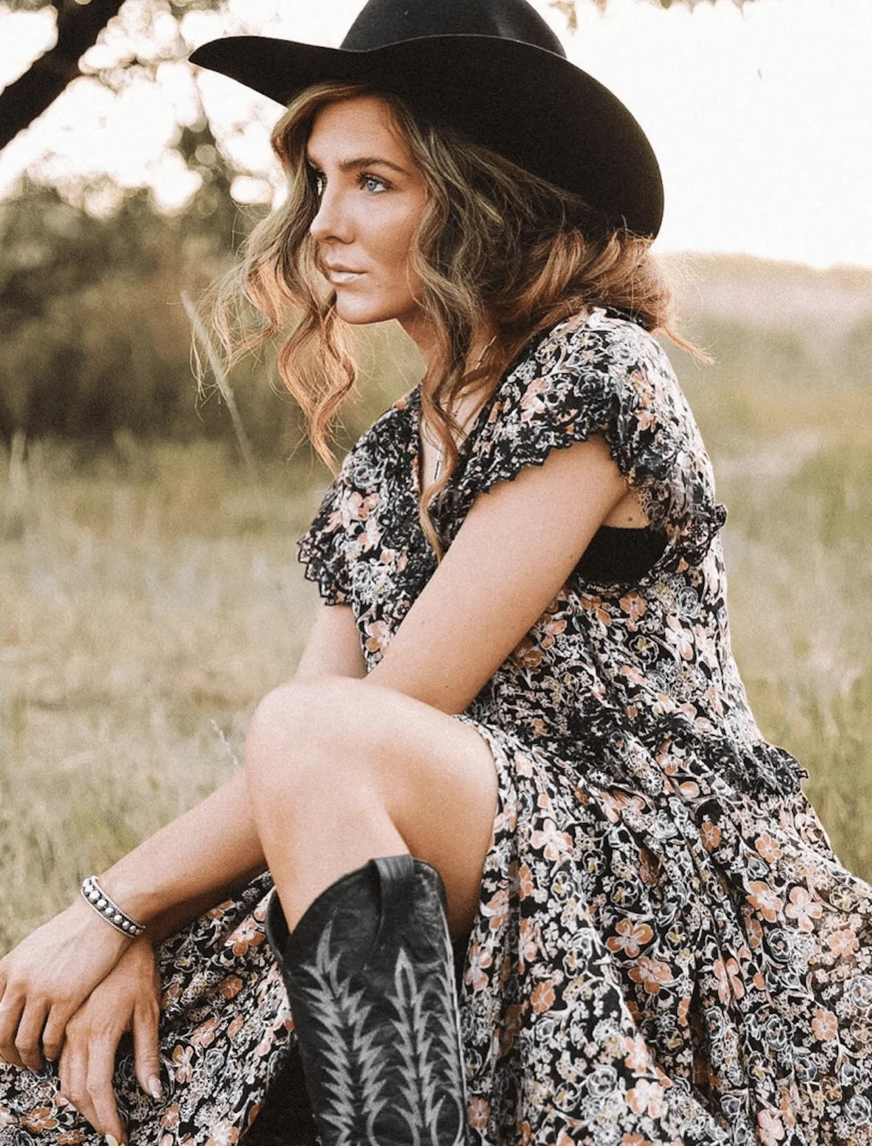 Woman in floral prairie dress with a straw cowboy hat and tan boots