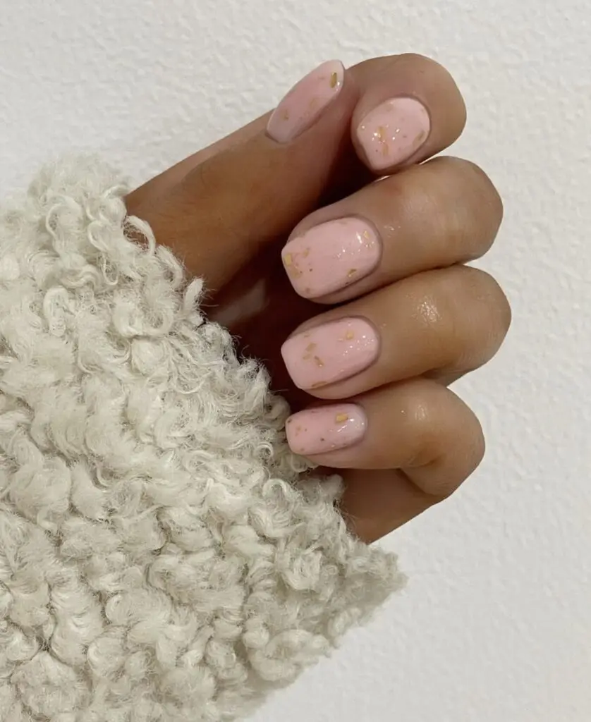 Short acrylic nails in a bright coral shade with a dotted gradient pattern