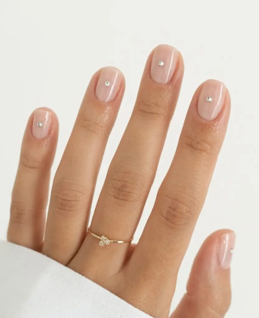 Short acrylic nails with neutral tones and golden glitter accents
