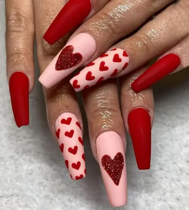Pale pink nails with heart-shaped glitter accents for Valentine’s Day