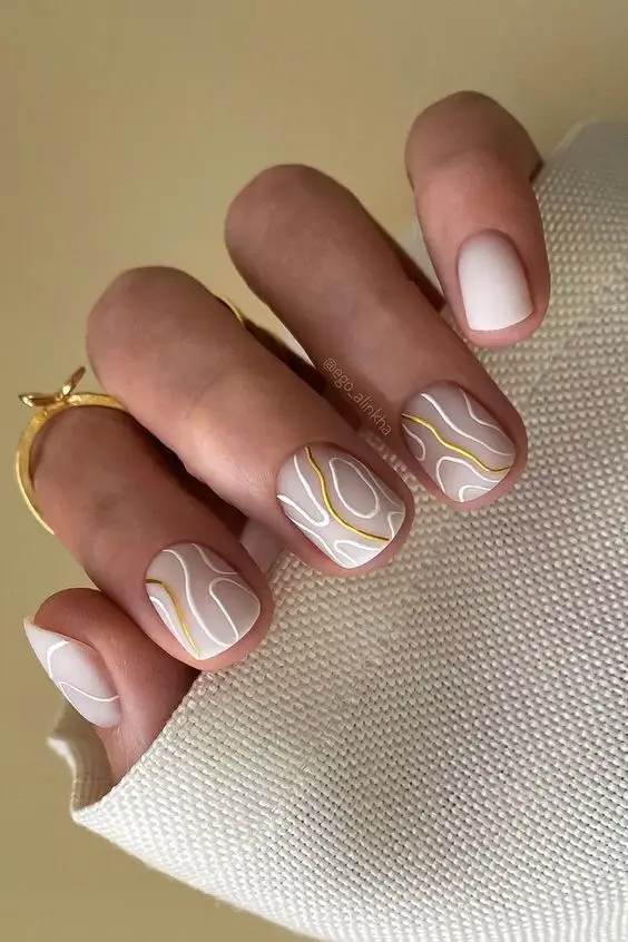 Short nude acrylic nails with gold foil accents