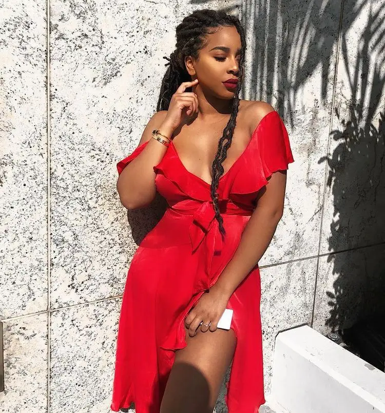 Black woman in a white cutout jumpsuit with braided sandals