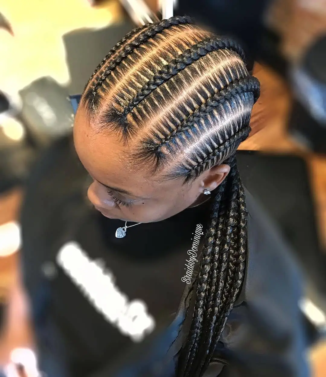 Side-swept chunky goddess cornrows with bold stitching and curls