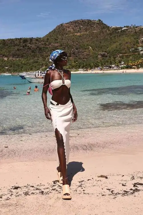 Woman Wearing a Tropical Print Romper with Straw Bag