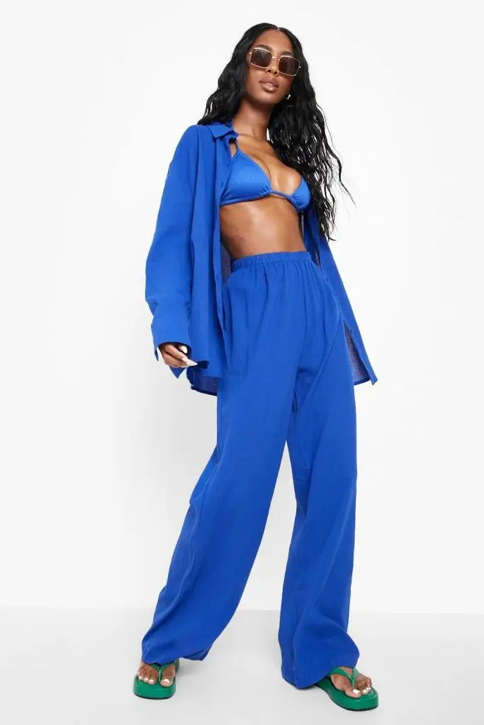 Black woman wearing organic cotton blue beach pants paired with a white sleeveless top
